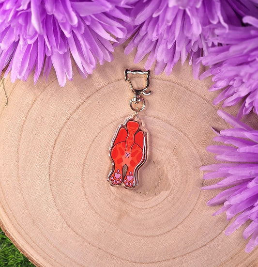 cat butt keyring on a wooden surface surrounded by purple flowers