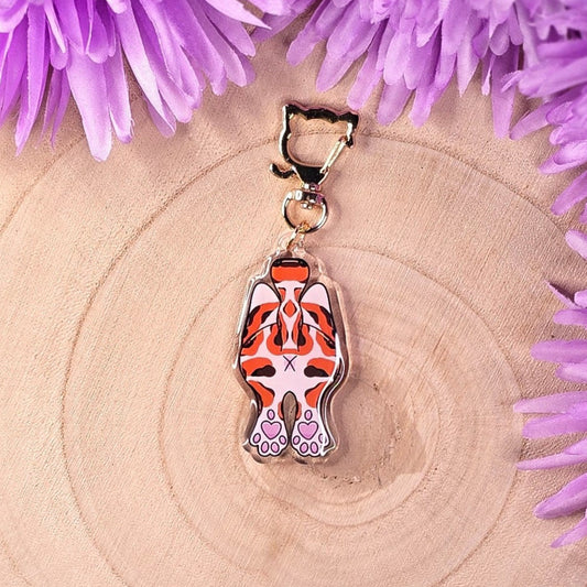 Tiger-shaped  cat butt keychain with pink accents on a wooden surface with purple flowers