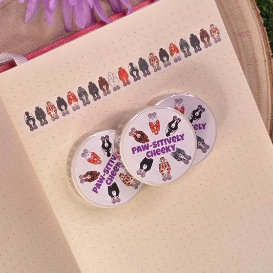 washi tape with cat buts on, resting on a book with purple flower in the background.