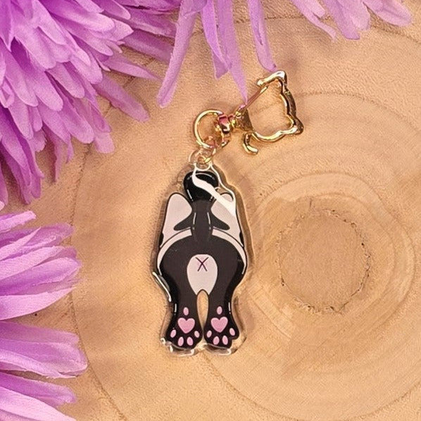 Cat-shaped keychain with pink heart paws on a wooden surface with purple flowers