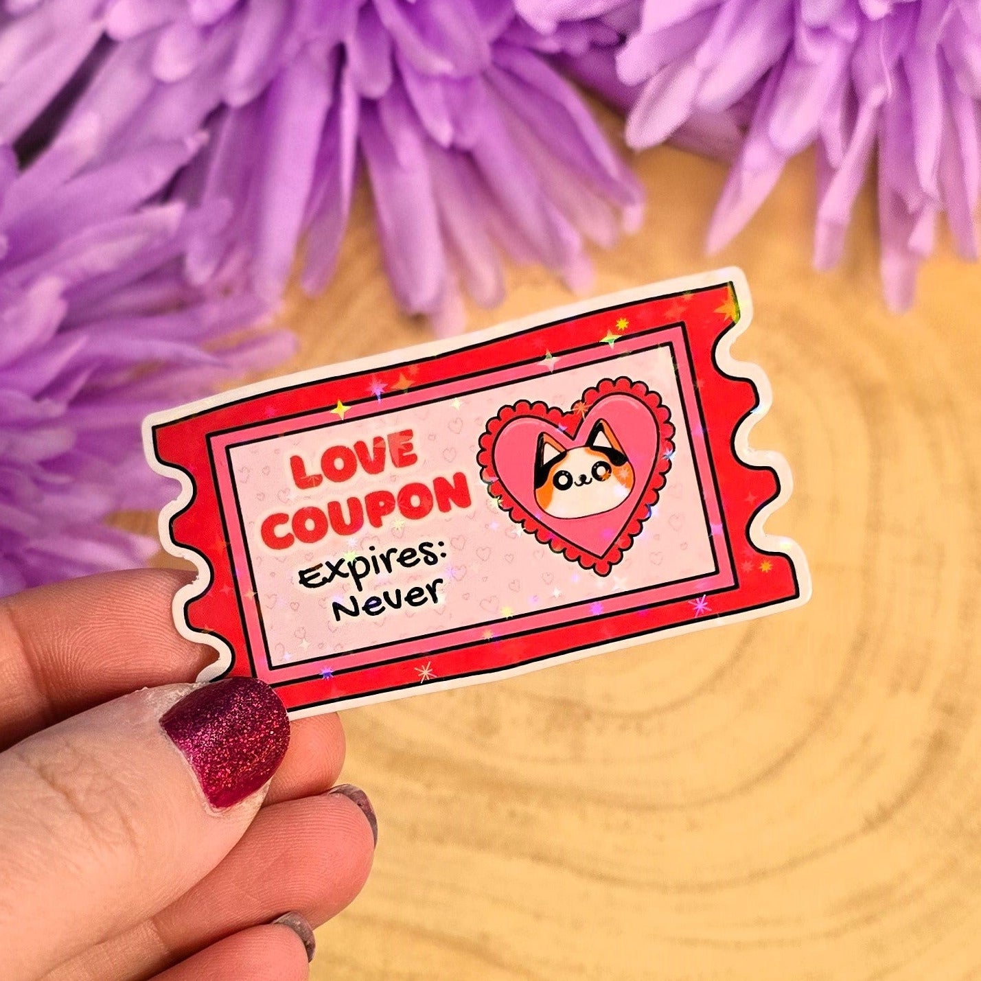 Hand holding a love coupon with a cartoon heart character against a background of purple flowers.