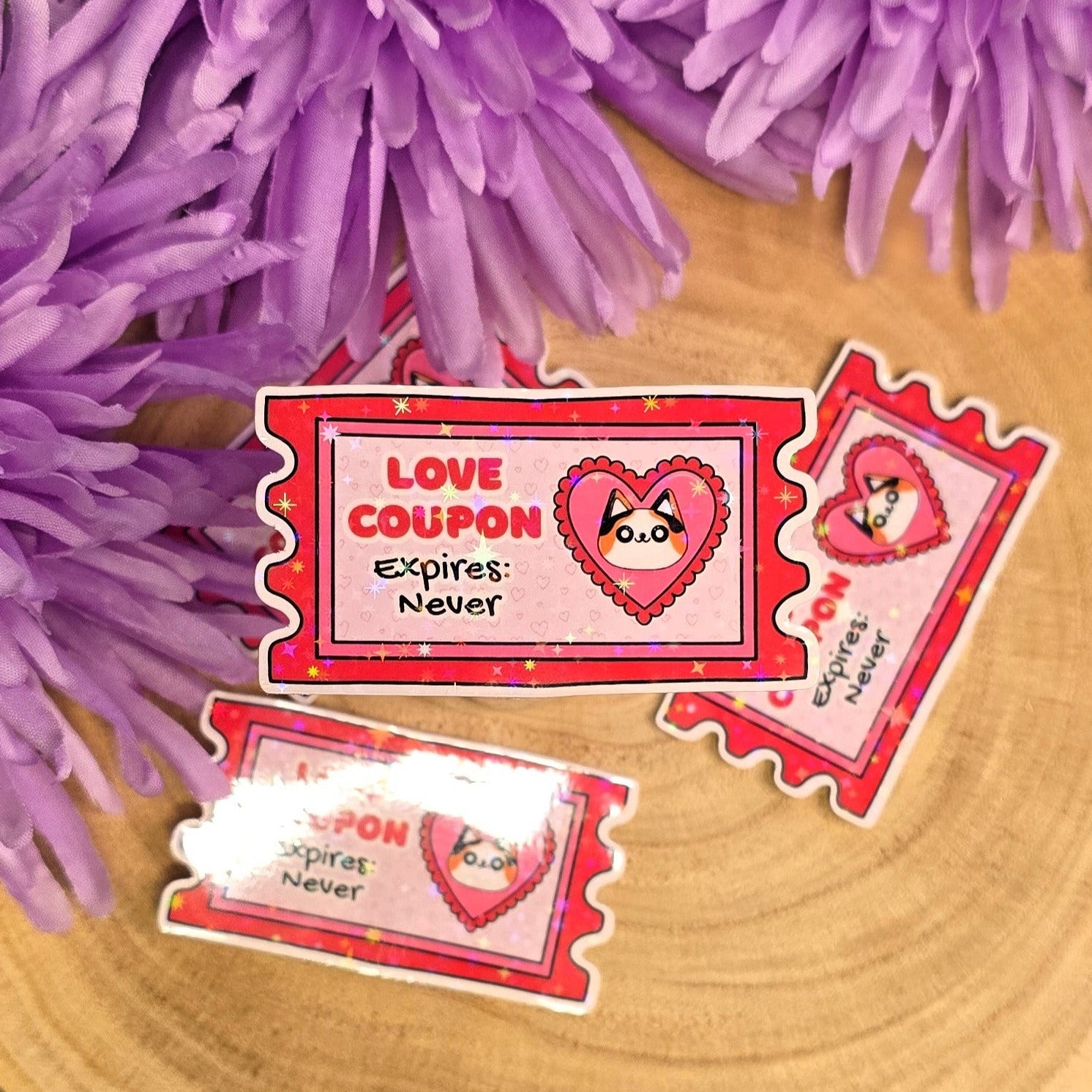 Red 'Love Coupon Expires Never' cards on a wooden surface with purple flowers.