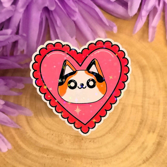 Heart-shaped sticker with a cat design on a wooden surface with purple flowers