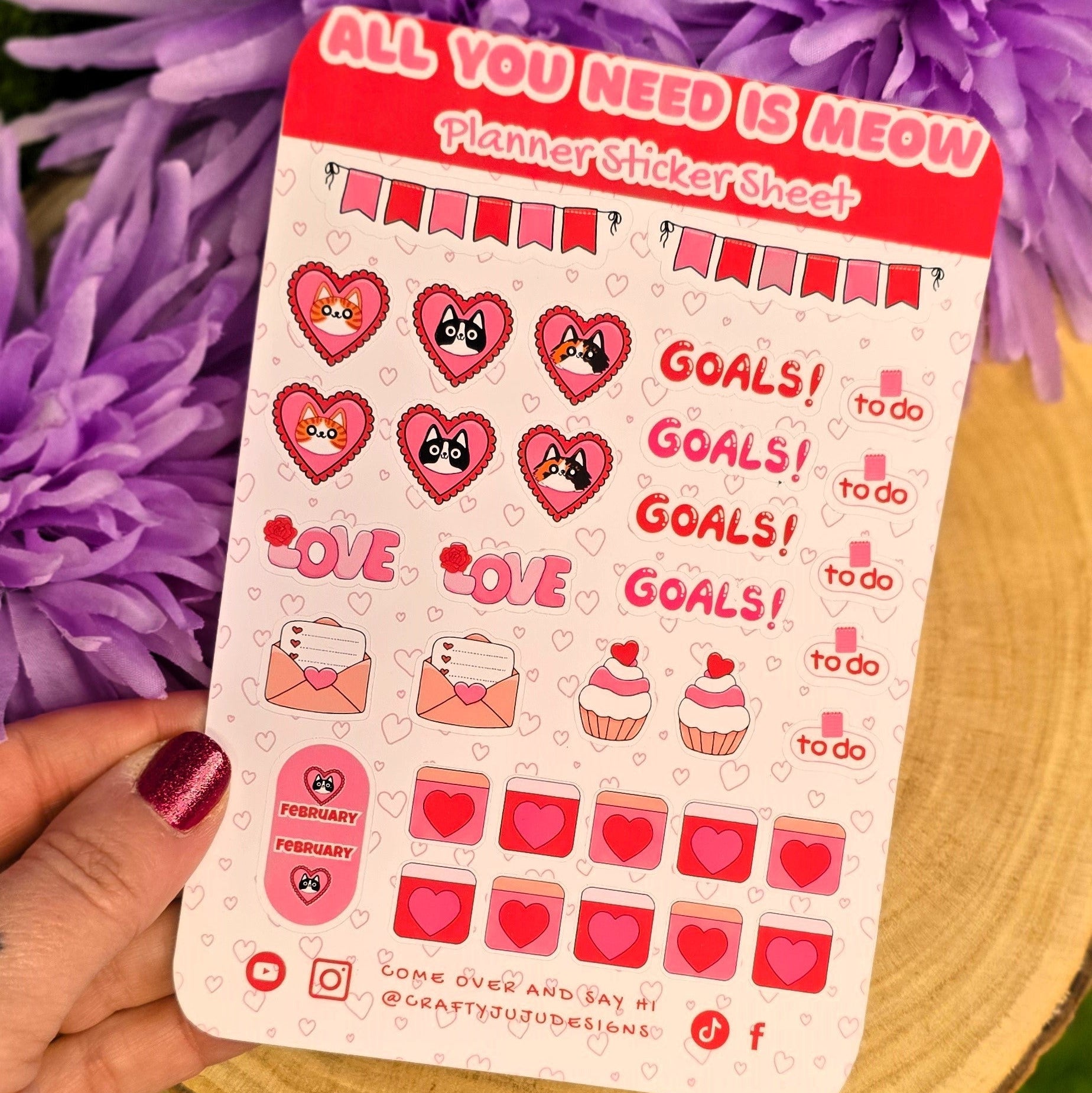 Sticker sheet with red and pink designs held over purple flowers