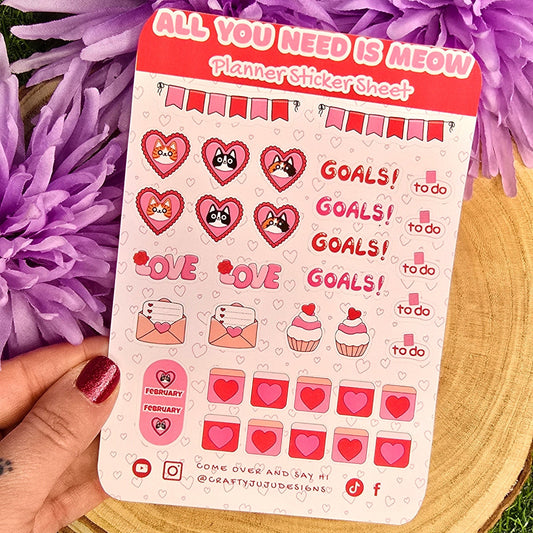 Sticker sheet with motivational designs held over purple flowers on a grassy background