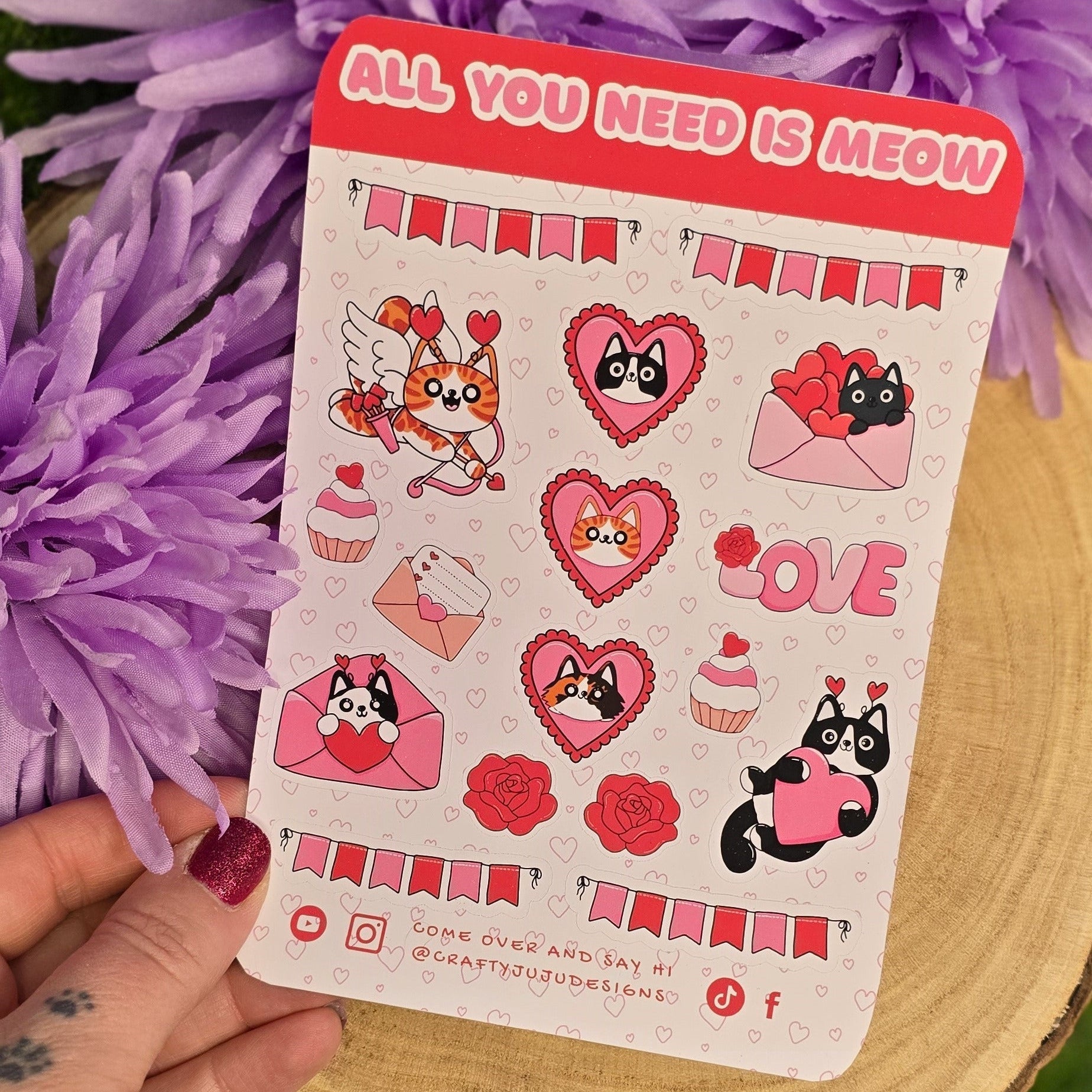 Card with stickers featuring cartoon characters and text held over purple flowers