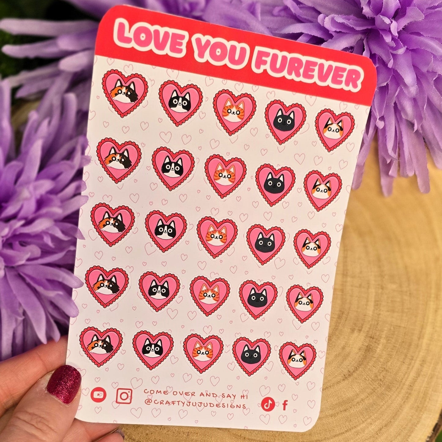 Sheet of heart-shaped stickers with cartoon faces held over purple flowers