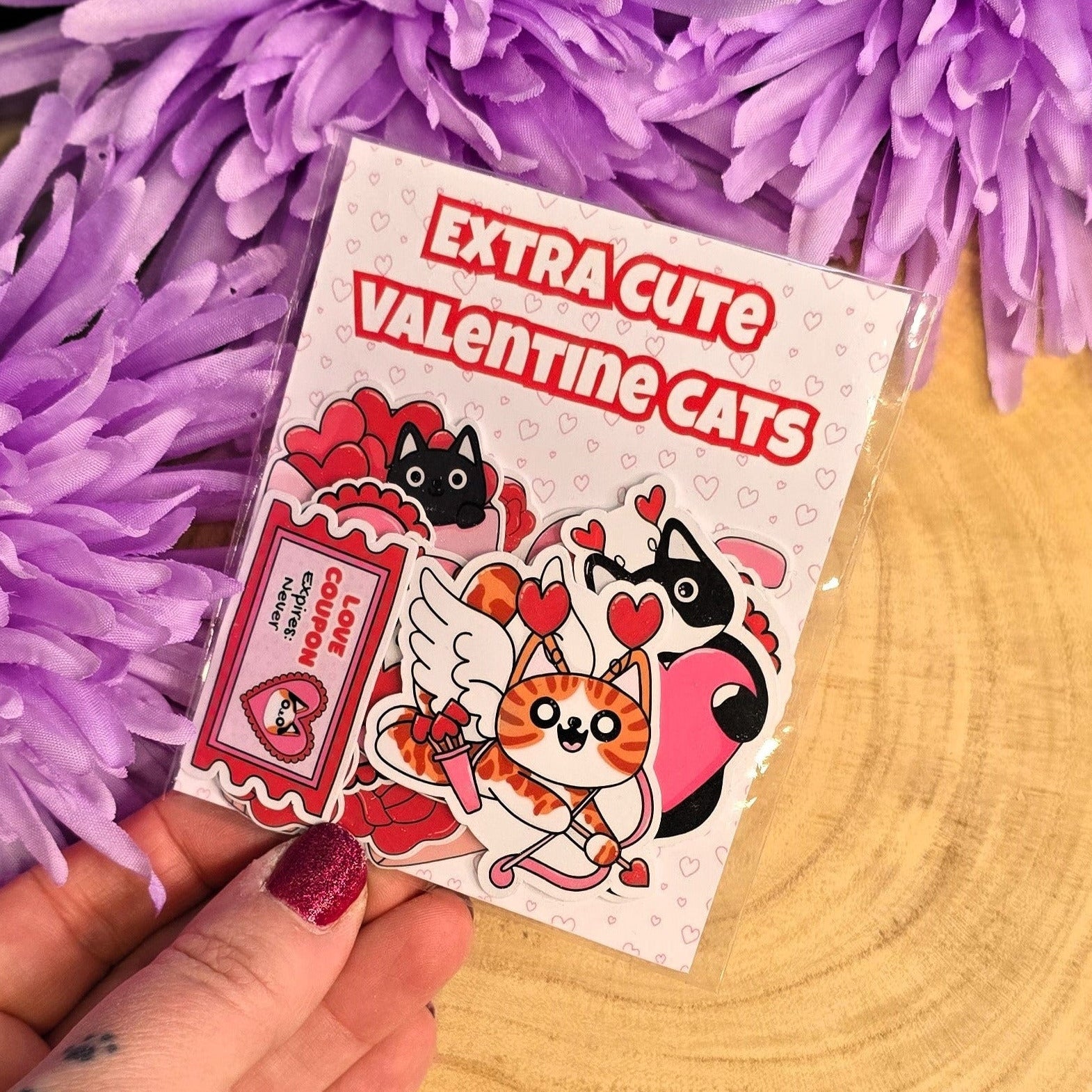 cat sticker pack held by a hand in front of purple flowers