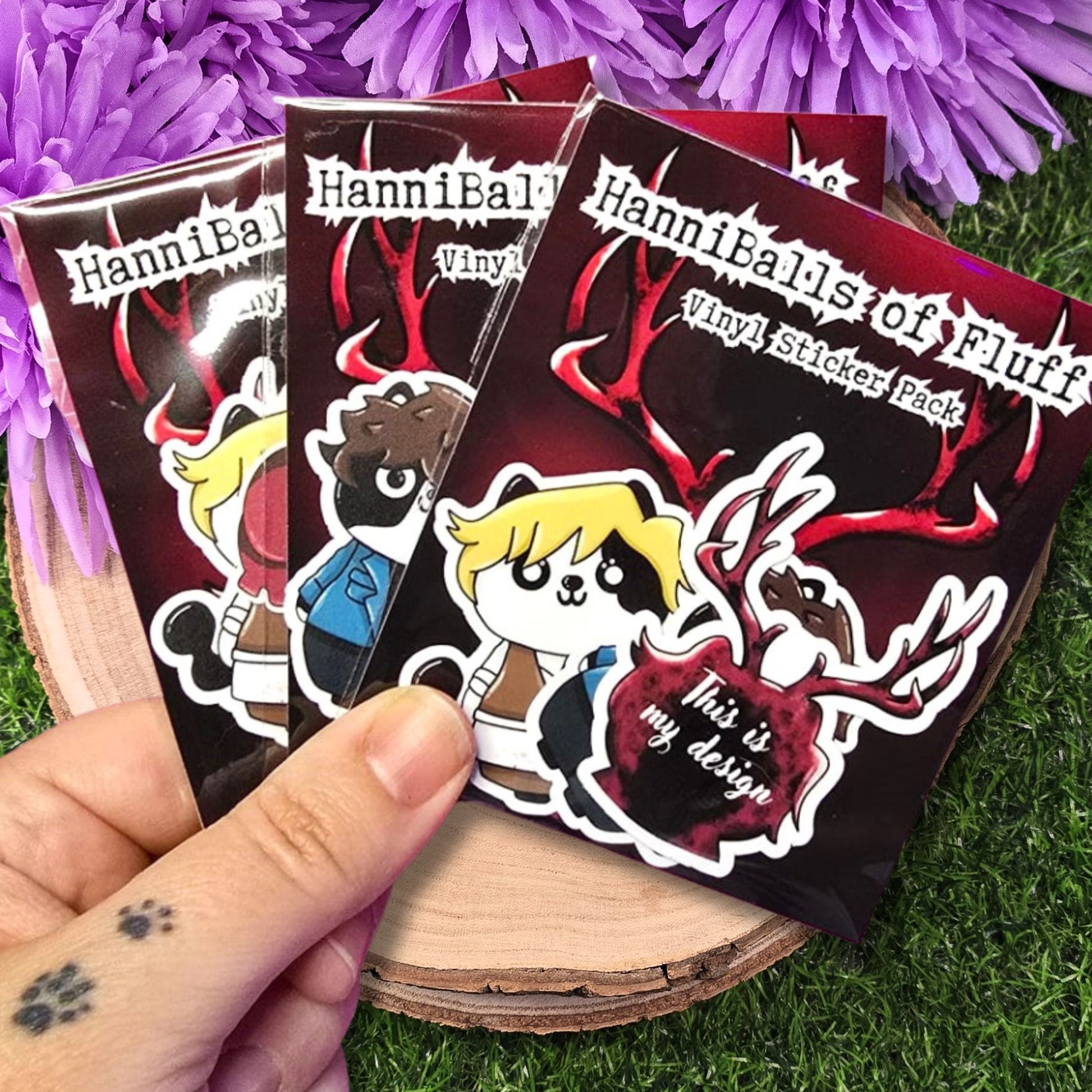 Hannibal Vinyl Sticker Pack held by a hand with purple flowers in the background