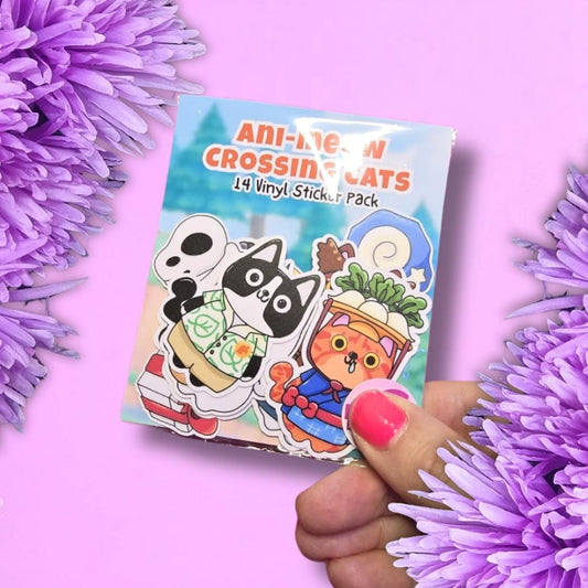 A hand with pink nail polish holds a sticker pack featuring cartoon cats, surrounded by purple flowers on a pink background. The sticker pack reads 'ANI-MESH CROSSING CATS 14 Vinyl Sticker Pack'.