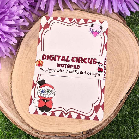 Digital Circus notepad with cartoon characters on a wooden surface with purple flowers.
