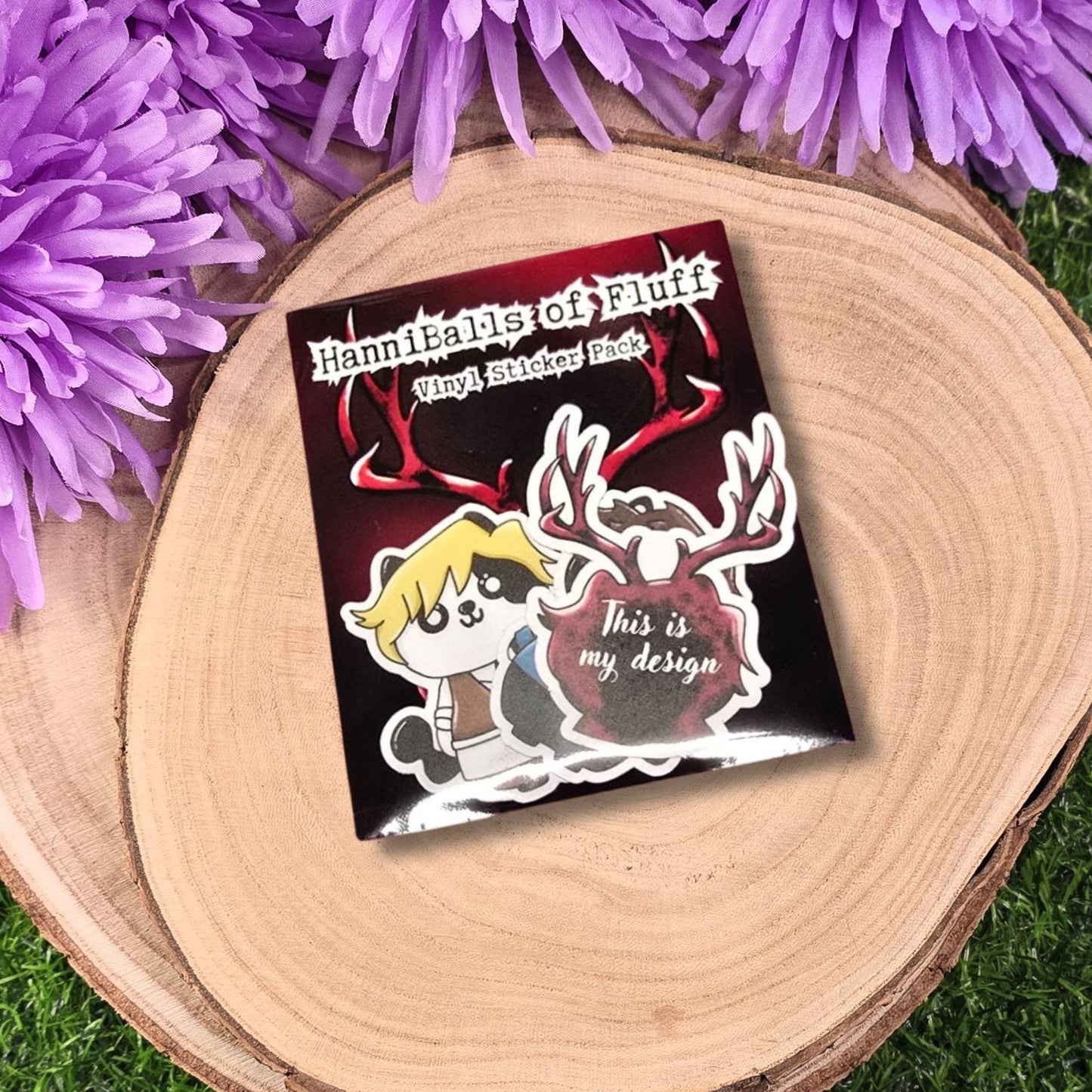 Sticker with cartoon hannibel character and text on a wooden surface with purple flowers