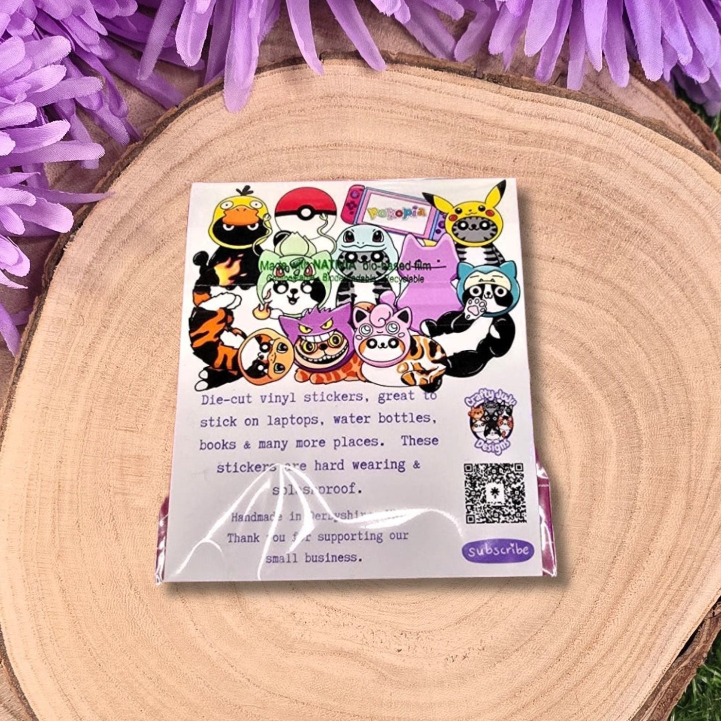 Pack of stickers with cartoon characters on a wooden surface with purple flowers.