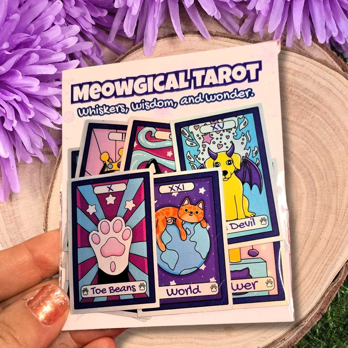 Meowgical Tarot card set with tarot card stickers and a purple flower on a wooden surface.