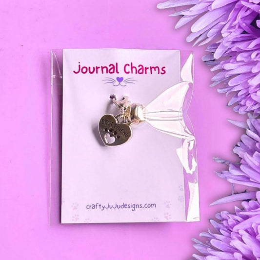 best friend heart clip on charm in its packaging on top of a purple background with purple flowers to the right