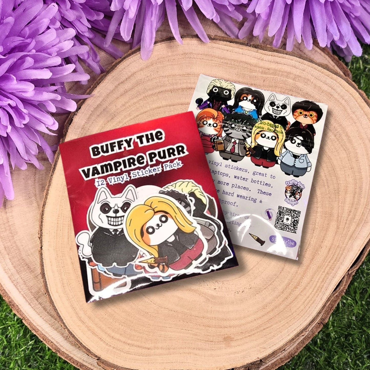 Sticker book titled 'Buffy the Vampire Purr' with stickers on a wooden surface surrounded by purple flowers.