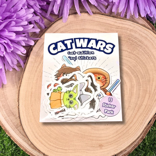 Sticker pack for 'Cat Wars' with cartoon characters on a wooden surface with purple flowers.