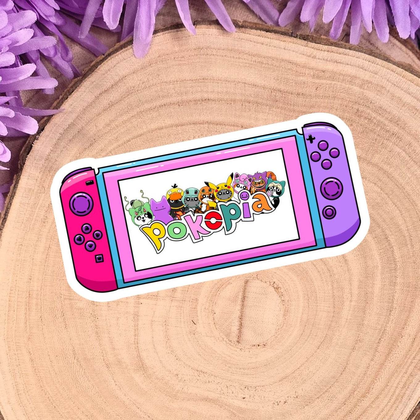 Colorful Pokémon logo sticker on a wooden surface with purple flowers.