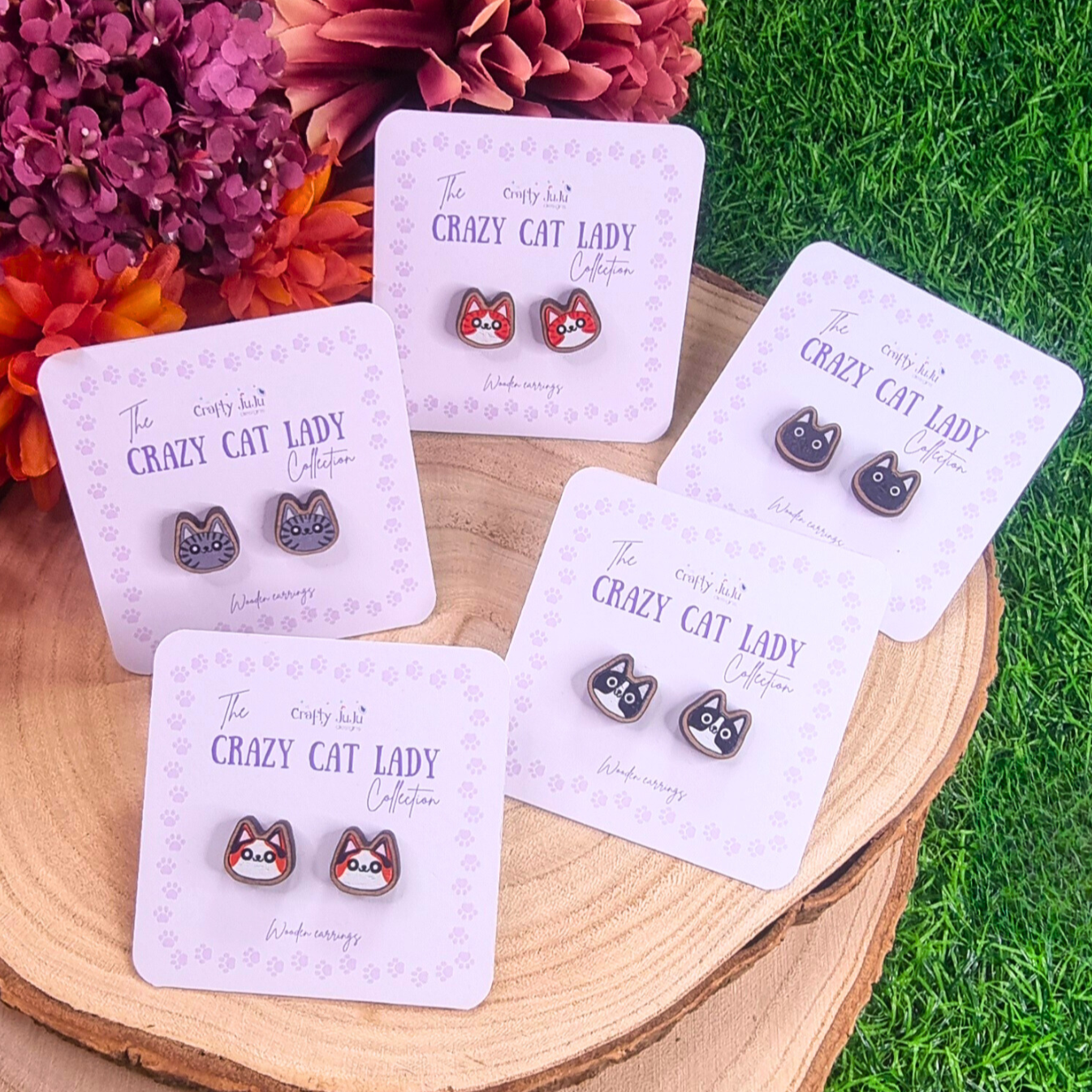 6 pairs of wooden cat earrings, grey cat, black and white cat, tortoiseshell cat, black cat and ginger and white cat.  Each pair is on a light purple backing card with The Crazy Cat Lady Collection labelled