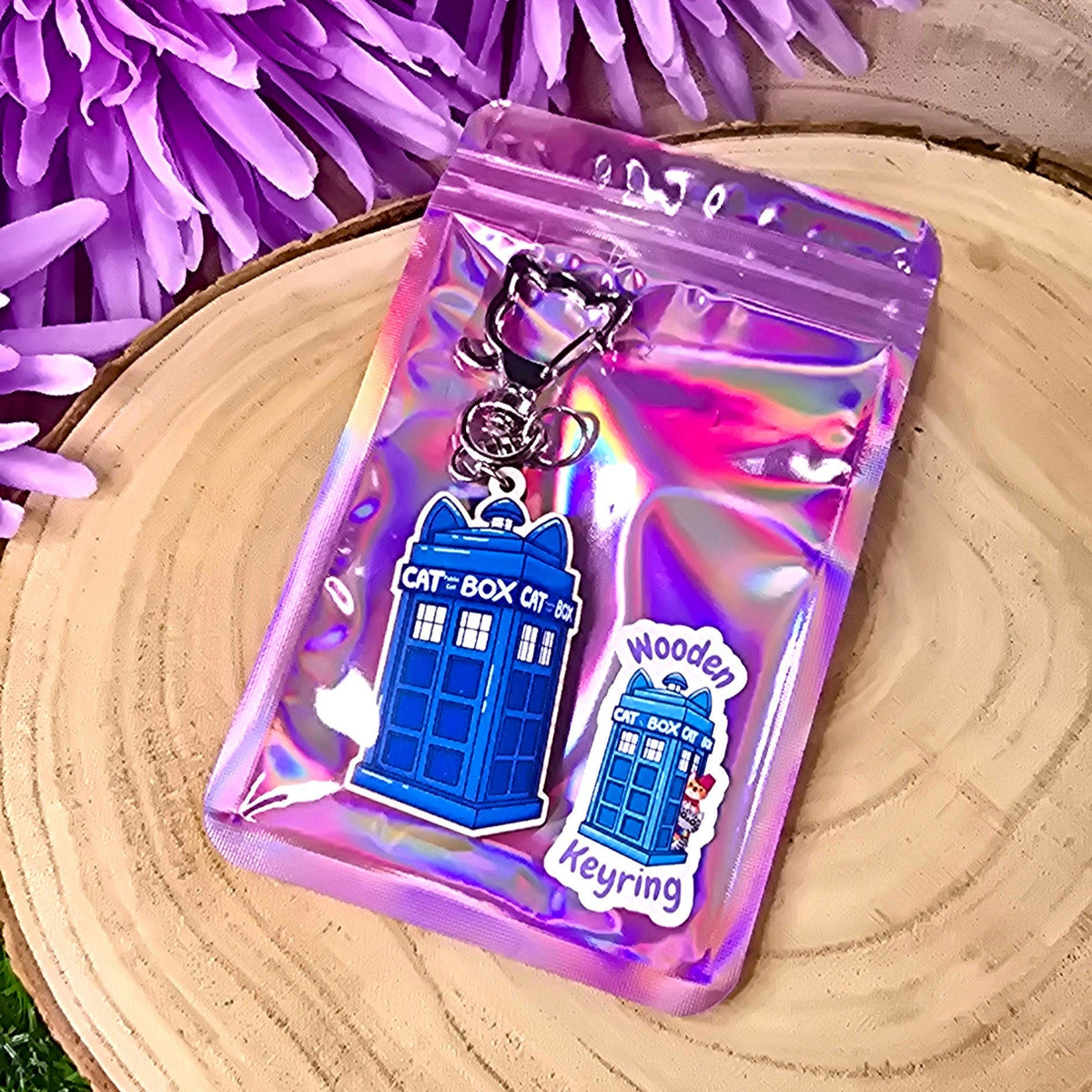 Futuristic keychain with a purple packaging on a wooden surface with purple flowers in the background
