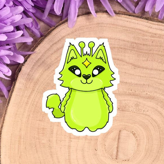 Green cartoon cat sticker on a wooden log with purple flowers
