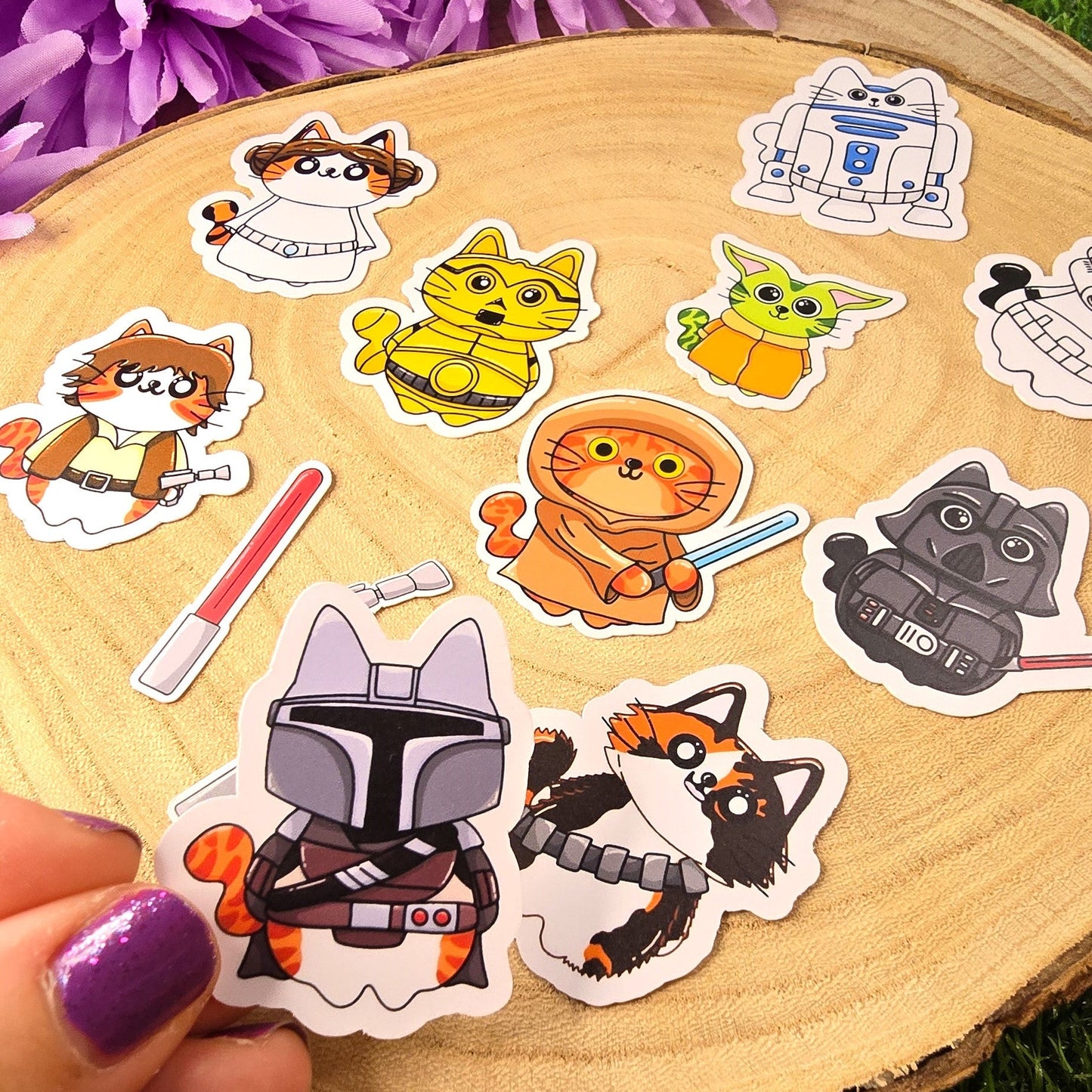 Collection of colorful stickers featuring cartoon characters on a wooden surface with purple flowers in the background.