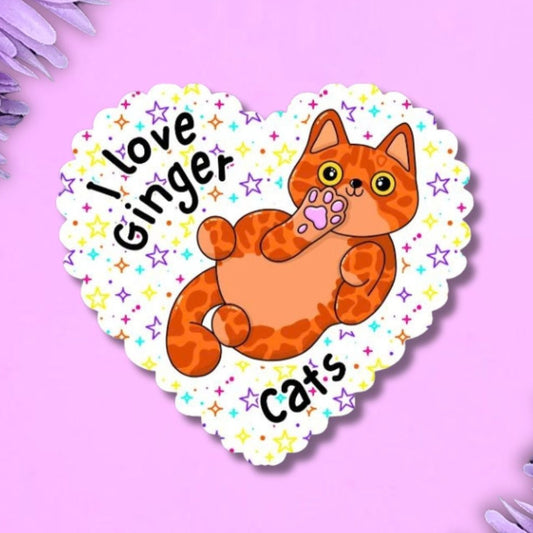 A heart-shaped sticker featuring an orange tabby cat illustration and the text 'I love Ginger Cats' on a white scalloped background, surrounded by purple flowers on a purple background.