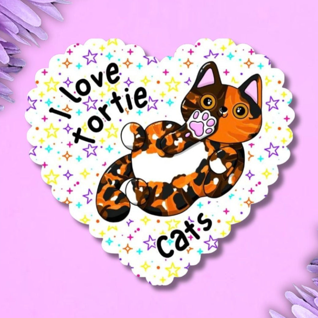 I love tortie cats large heart shaped sticker with scalloped edge. The background is white with multi coloured stars. The cat is on its back showing off its belly