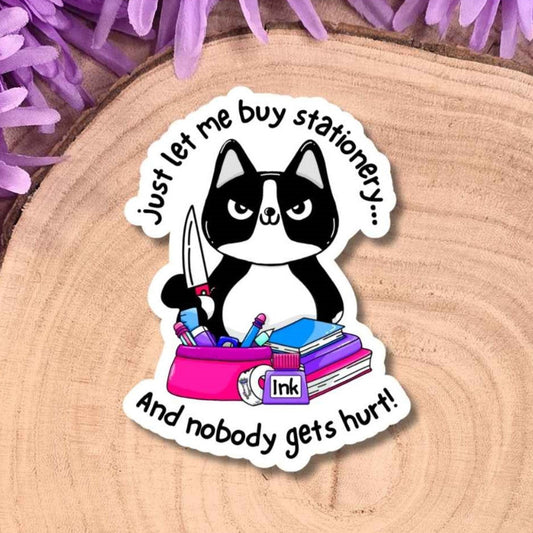 A die-cut sticker featuring a black and white cat sitting behind stationery, holding a knife surrounded by the text 'just let me buy stationery...and nobody gets hurt!