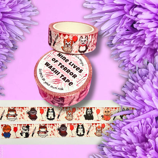 washi tape featuring 9 of my terror cats. set on white tape with blood splatters on the tape and then 9 of my horror cats along it. The tape is set on a lilac background with lilac flowers around the edges
