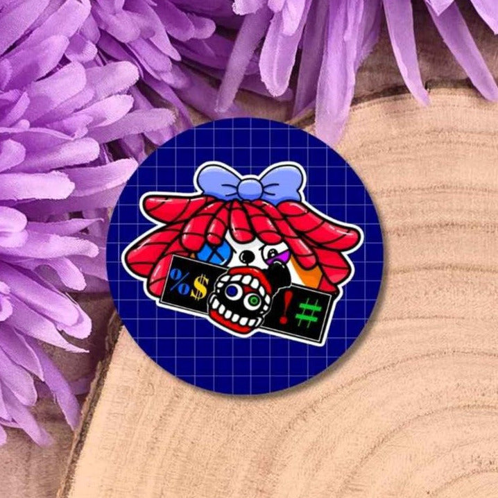 A round sticker featuring a cartoon character with a red hair, a blue bow, placed on a wooden surface with purple flowers in the background.