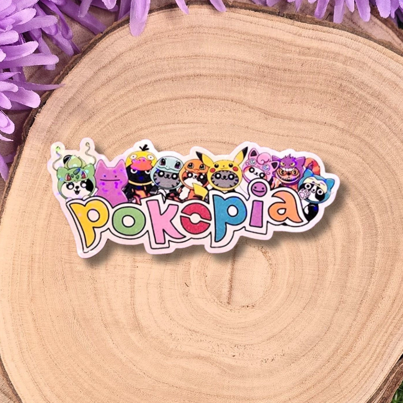 Colorful 'Pokopial' sticker with cartoon characters on a wooden surface with purple flowers.