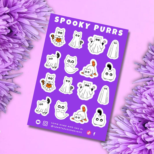A purple sticker sheet titled 'Spooky Purrs' featuring cartoon cat and ghost Halloween designs, styled on a pink background with purple flowers.