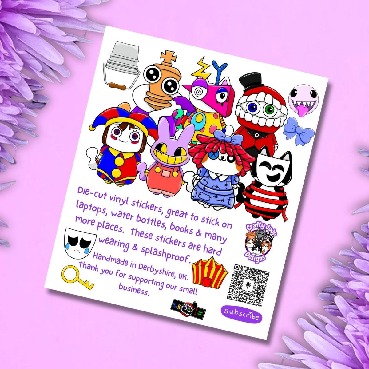 A sheet of colorful cartoon die-cut vinyl stickers displayed on a light pink background framed by purple flowers. The stickers feature various whimsical characters, text reading 'Die-cut vinyl stickers, great to stick on laptops, water bottles, books & many more places.
