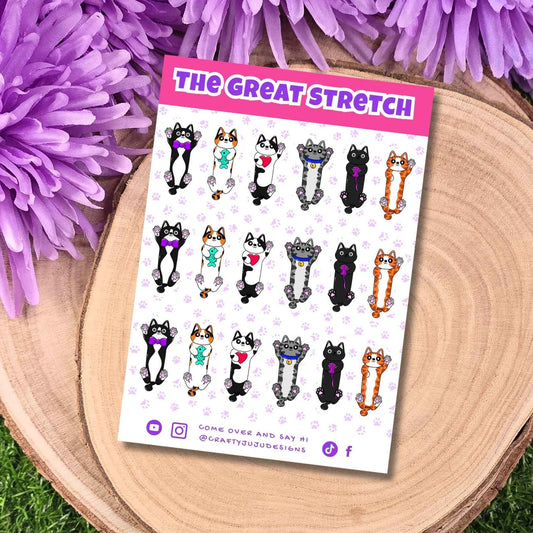 A sticker sheet titled 'THE GREAT STRETCH' featuring cartoon cat illustrations in various poses, displayed on a round wooden slice with purple flowers around it.